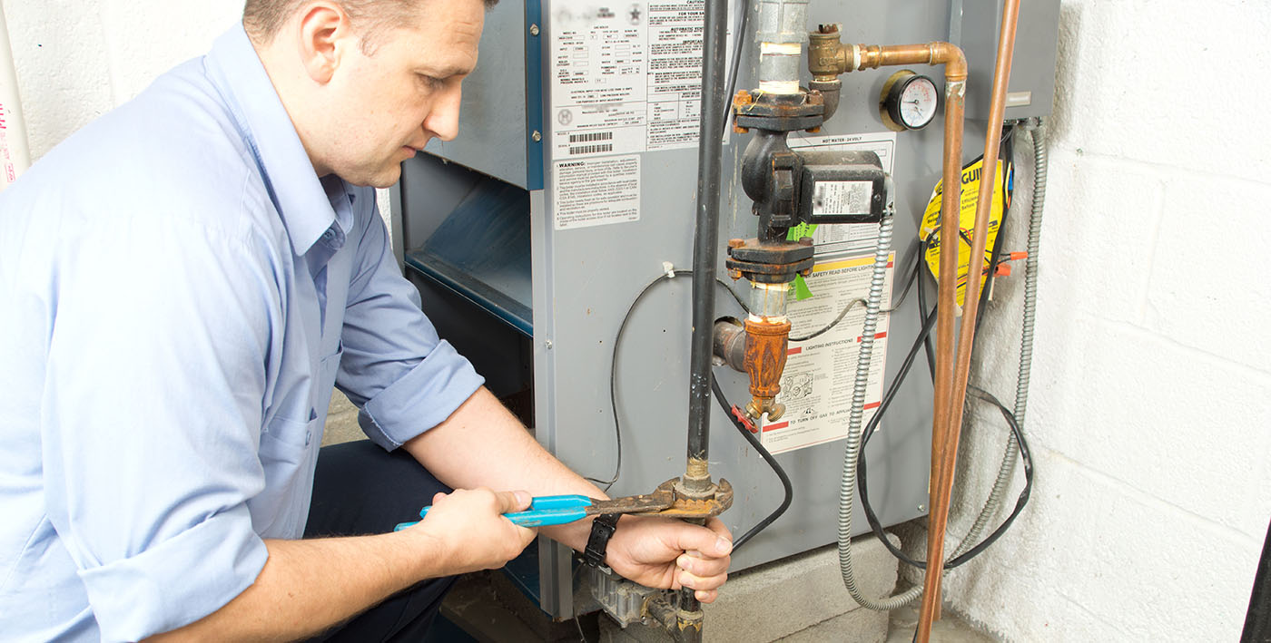 Technician repairing a basement forced air furnace in Wasilla, AK